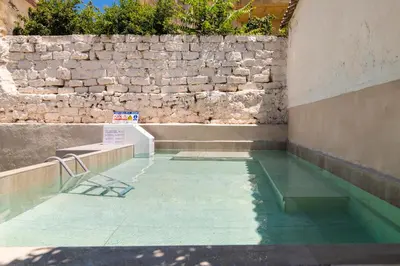a room with a pool of water next to a stone wall at Lefka Home in Rhodes Town