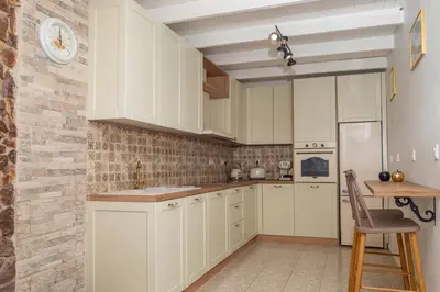 a kitchen with white cabinets and a brick wall at Giannis House in Rhodes Town