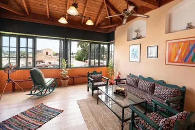 a living room with couches and chairs and windows at Labyrinthos Arts Guest House in Rhodes Town