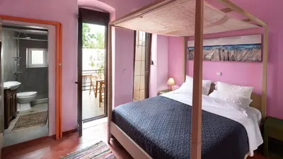 a bedroom with a canopy bed and a bathroom at Labyrinthos Arts Guest House in Rhodes Town