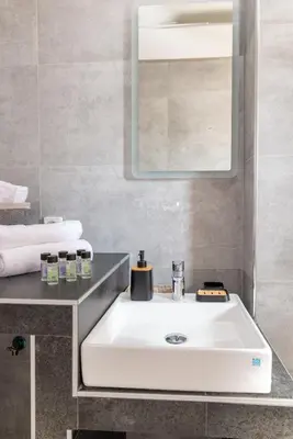 a bathroom with a white sink and a mirror at Katerina & Stefanos Family apartments in Archangelos