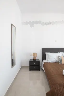 a bedroom with a bed and a nightstand with a mirror at Katerina & Stefanos Family apartments in Archangelos