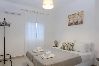 a white bedroom with two towels on a bed at Katerina & Stefanos Family apartments in Archangelos
