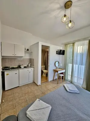 a kitchen and a living room with a bed and a table at Lindos Tsambika Studios in Líndos