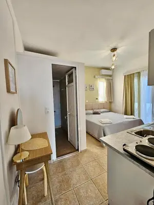 a room with a kitchen and a bedroom with a bed at Lindos Tsambika Studios in Líndos