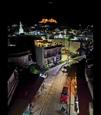 a city at night with cars parked on a street at Archangelos SKY Garden Apartment in Archangelos