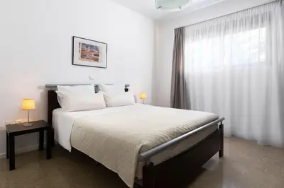 a white bedroom with a large bed with a window at Luxurious and modern house near town and beach in Asgourou