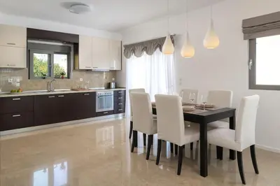 a kitchen with a dining room table and white chairs at Luxurious and modern house near town and beach in Asgourou