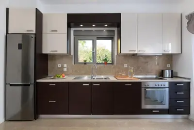a kitchen with white cabinets and a stainless steel refrigerator at Luxurious and modern house near town and beach in Asgourou