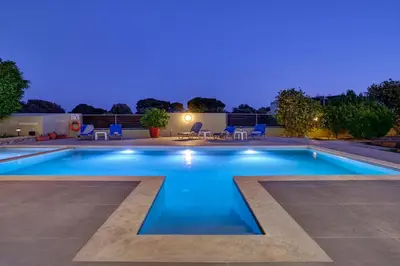 a swimming pool in a backyard at night at Gia's Luxury Residence in Asgourou
