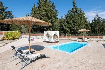 a swimming pool with two chairs and an umbrella at Physis Luxury Villa in Archangelos