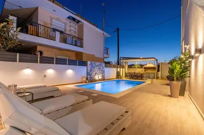 a villa with a swimming pool in front of a building at Grande Terra in Kiotari