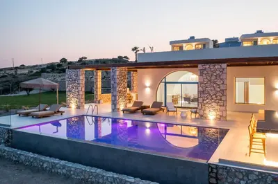 a villa with a swimming pool in front of a house at Athoros Luxury Villas in Afantou