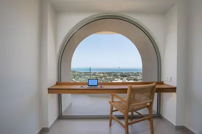 an arched window with a desk and a laptop on it at Athoros Luxury Villas in Afantou