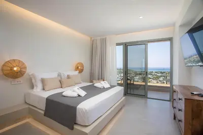 a bedroom with a large bed and a large window at Athoros Luxury Villas in Afantou