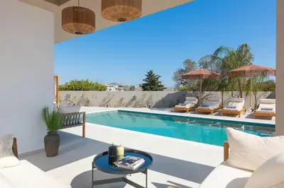 a villa with a swimming pool with chairs and a table at Golf Beach Villa in Afantou