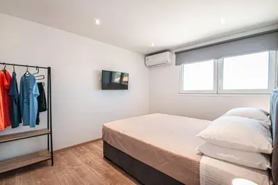 a white bedroom with a bed and a window at Rhodes Sunset House in Rhodes Town