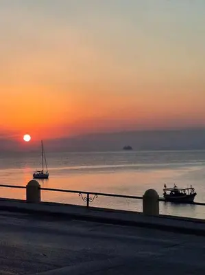 two boats in the ocean with the sunset in the background at Rhodes Sunset House in Rhodes Town