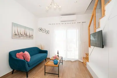 a living room with a blue couch and a tv at Rhodes Sunset House in Rhodes Town