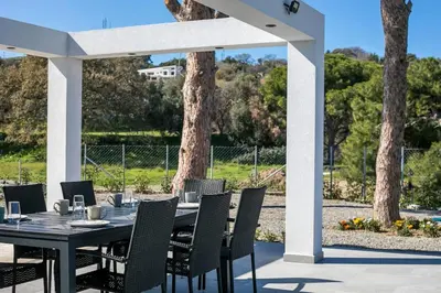 a black table and chairs under a white pergola at Villa Seranti in Asgourou