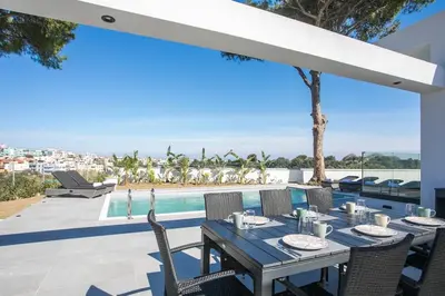 a table and chairs on a patio with a swimming pool at Villa Seranti in Asgourou
