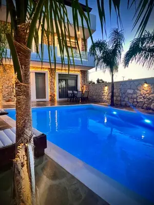 a swimming pool in front of a villa at Odyssea Front Beach in Kremasti