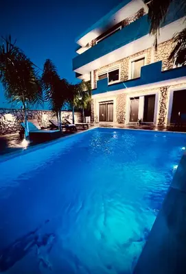 a swimming pool in front of a house at night at Odyssea Front Beach in Kremasti