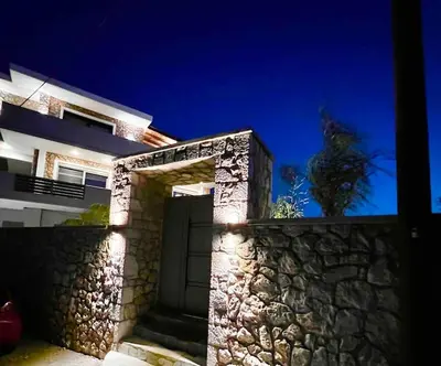 a house with a stone wall and a door at Odyssea Front Beach in Kremasti