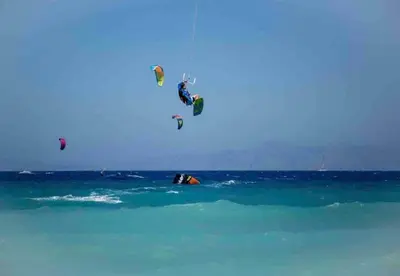 a group of people are flying over the ocean at Odyssea Front Beach in Kremasti
