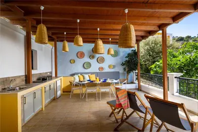 an outdoor kitchen with a table and chairs on a balcony at Symiland Villa in Symi