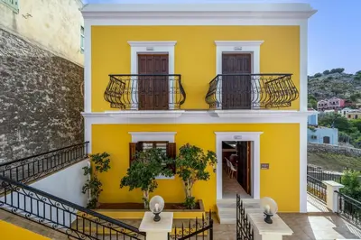 a yellow house with two balconies and a staircase at Symiland Villa in Symi