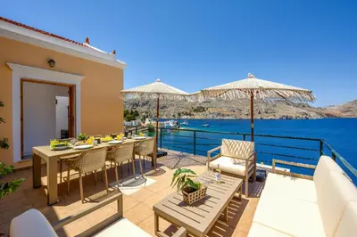 a patio with tables and chairs and a view of the water at Nimporio View Villa in Symi