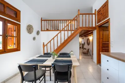 a dining room with a table and chairs and a staircase at Nimporio View Villa in Symi