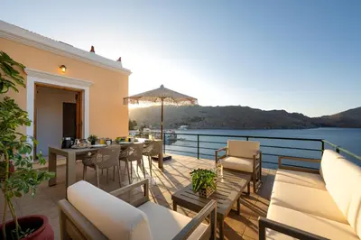 a balcony with a table and chairs and a view of the water at Nimporio View Villa in Symi