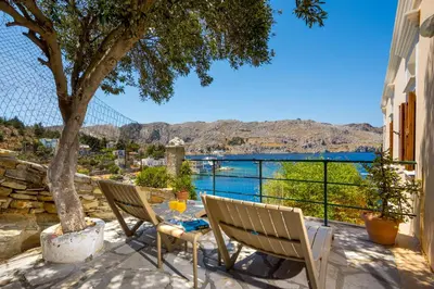 a patio with two chairs and a table and a tree at Nimporio View Villa in Symi