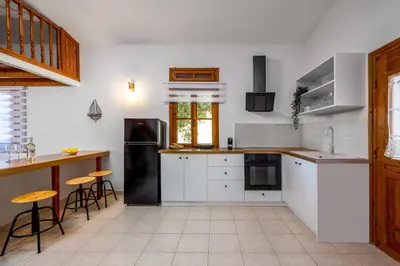 a kitchen with white cabinets and a black refrigerator at Nimporio View Villa in Symi
