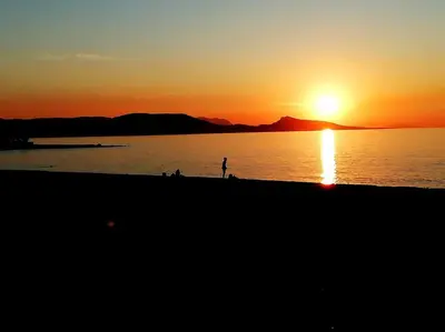 a person standing on the beach at sunset at TinyVibe - Downtown Seabreeze Studio in Rhodes Town