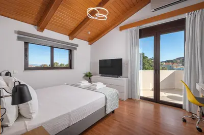 a bedroom with a bed and a flat screen tv at Greenheart - Mediterranean Elegance in Nature in Ialyssos