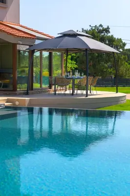 a table and chairs under an umbrella next to a swimming pool at Greenheart - Mediterranean Elegance in Nature in Ialyssos