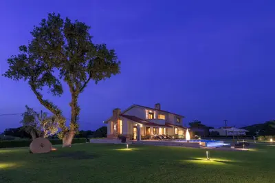 a house with lights on the lawn at night at Greenheart - Mediterranean Elegance in Nature in Ialyssos