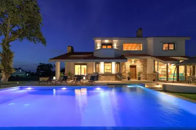 a large swimming pool in front of a house at night at Greenheart - Mediterranean Elegance in Nature in Ialyssos
