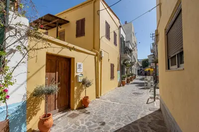 an alley with yellow buildings and potted plants at Mascot Memories in Rhodes Town