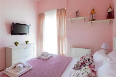 a pink bedroom with a bed with towels on it at Ivi CentralApartment Rhodes Town in Rhodes Town