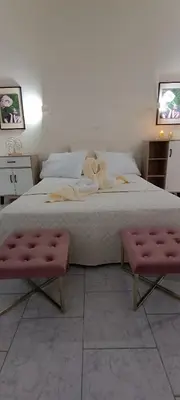 a bedroom with a large bed with two pink benches at Pyrgos Hotel Apartments in Kremasti