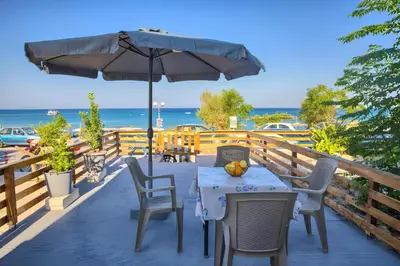 a table and chairs on a deck with an umbrella at La mer stegna in Archangelos
