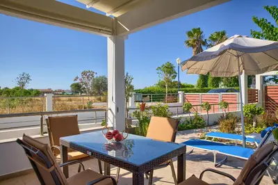 a patio with a table and chairs and an umbrella at Paul’s Garden Luxury House in Haraki
