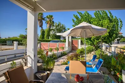 an outdoor patio with chairs and an umbrella at Paul’s Garden Luxury House in Haraki