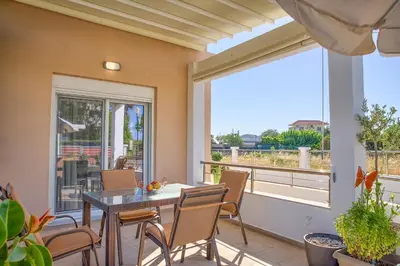 a patio with a table and chairs and a large window at Paul’s Garden Luxury House in Haraki