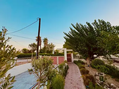 a house with a fence and a tree and a sidewalk at Paul’s Garden Luxury House in Haraki