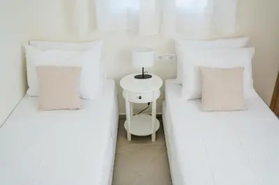 two beds with white pillows and a lamp on a side table at Alcestis City Apartment in Rhodes Town